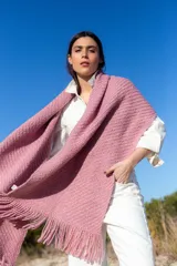 Chal de tejido de punto con textura acanalada, color rosa, con terminación de flecos en los extremos y etiqueta de cuero con logo de la marca.