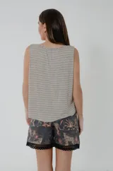Remera de algodón con diseño de rayas finas horizontales en color beige y negro, sin mangas, con escote cuadrado decorado con un ancho galón de puntilla estilo vintage y sisa con ribete. Presenta un corte inferior redondeado.