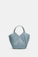 Bolso mini shopper de cuero sintético en color celeste, con diseño estructurado de paneles geométricos y costuras decorativas en contraste. Cuenta con doble asa de mano y cierre magnético.