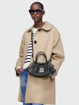 Cartera satchel pequeña de cuero negro con diseño fruncido en la parte superior, doble asa de mano y correa ajustable para llevar al hombro o cruzada. Incluye cierre metálico frontal con logo grabado.