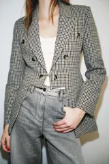 Blazer Zara de corte asimétrico confeccionado en tejido con lana. Presenta un diseño de cuadros, cuello con solapas de muesca, manga larga y cierre frontal cruzado con botones. El bajo es asimétrico con una abertura pronunciada en la espalda y cuenta con forro interior.