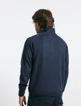 Sweater de punto color azul marino, con cuello alto, cierre frontal parcial y tapeta con botones. Presenta mangas raglán y puños y ruedo acanalados.