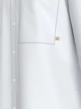 Camisa blanca de algodón Oxford con cuello estructurado, cierre frontal con botones, bolsillo en el pecho y logo Calvin Klein bordado en el pecho.