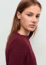 Vestido corto bordó con cuello barco, manga larga y diseño entallado con fruncidos laterales.