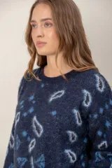 Sweater de punto con textura suave, color azul marino con estampado de formas abstractas y rombos en tonos celestes y grises. Presenta cuello redondo y mangas largas con diseño holgado.