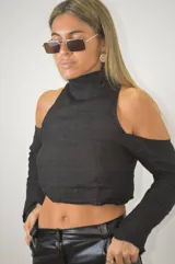 Blusa corta negra con cuello alto, hombros descubiertos y mangas largas.