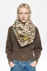 Cuello de pelo sintético con estampado animal print en tonos beige y blanco, con cierre de botones frontales.