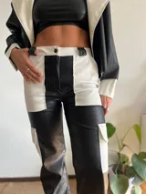 Pantalón cargo de cuero sintético con diseño bicolor en blanco y negro y textura tipo piel de cocodrilo. Presenta bolsillos laterales tipo cargo y corte recto.