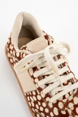 Zapatilla de cuero con textura de pelo y estampado animal print de puntos, con detalles en cuero liso color crema en los laterales y talón, y suela de goma color caramelo.