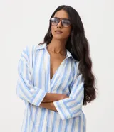 Salida de playa tipo camisa confeccionada en voile de algodón, con diseño de rayas verticales en tonos celeste y blanco, cuello tradicional y mangas 3/4.