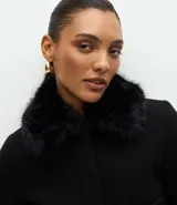 Saco corto de polivelour negro con cuello de piel sintética, cierre frontal oculto, bolsillos cargo delanteros con solapa y detalles de botones en los puños.