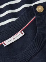 Sweater de Tommy Hilfiger con diseño de rayas horizontales en azul marino y blanco. Presenta cuello redondo, manga larga y detalle de botones decorativos dorados en uno de los hombros.