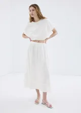 Falda midi evasé de color blanco, confeccionada en algodón con detalles bordados tonales, cintura elástica y forro interior.