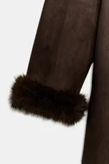 Abrigo largo de Zara Woman Collection en color marrón chocolate, con cuello de solapa amplio, mangas largas y cinturón ajustable del mismo tejido. Presenta detalles de forro interior y acabados en efecto pelo a tono en cuello, puños y bordes frontales.