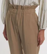Pantalón carrot color tostado de viscosa, con cintura elástica fruncida, cierre frontal con cremallera y bolsillos laterales.