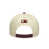 Gorra de béisbol New Era color beige con visera y botón superior color borgoña. Presenta el logo de los New York Yankees bordado en el frente y el logo de New Era bordado en el lateral.