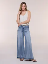 Jean wide leg de tiro alto en denim azul claro, con calce ajustado en la cadera, costuras verticales frontales y bolsillos estilo carpintero.