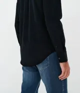 Camisa de manga larga confeccionada en terciopelo de algodón, con cuello clásico, cierre frontal con botones y bolsillo en el pecho.