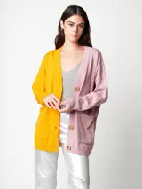 Cárdigan de punto fino bicolor, con un lado amarillo y otro rosado. Tiene bolsillos delanteros y cierre con botones de madera.
