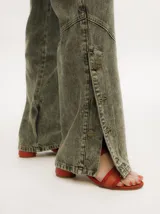 Pantalón de jean de corte recto y tiro medio, con efecto gastado. Presenta una hilera de botones en los laterales de los botapiés y bolsillos delanteros y traseros.