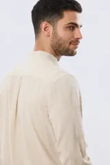 Camisa de lino y algodón color blanco, con cuello mao, manga larga y cierre frontal de botones. Presenta un pequeño logo bordado en el pecho.