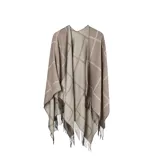 Poncho abierto de tejido de punto con diseño de cuadros grandes en tonos beige y marrón, con terminaciones de flecos en el ruedo.