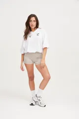 Camiseta blanca de poliéster microperforado con cuello en V y mangas cortas. Diseño oversize con cordón ajustable en la cintura y estampado minimalista con el número 17 y el logo de la marca en verde.