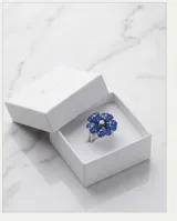 Anillo de plata 925 con diseño de flor, decorado con incrustaciones de piedras azules y un centro brillante.