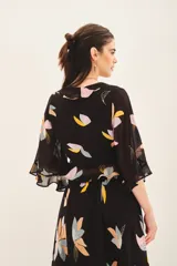 Camisa corta tipo crop top de viscosa georgette con estampado floral. Presenta mangas amplias con volados y detalle de volado en la cintura. Incluye forrería a tono.
