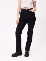 Jean de corte recto y tiro alto, color negro, con costuras verticales decorativas en el frente de las piernas. Cuenta con cierre y botón metálico, además de bolsillos laterales y traseros.