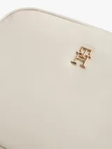 Cartera bandolera rectangular de tejido técnico color beige, con cierre de cremallera, correa tejida ajustable y extraíble, y detalle de monograma TH metálico en la parte delantera.