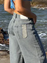 Pantalón jean celeste de corte wide leg, con bolsillos delanteros y traseros, y detalle de parche en uno de los bolsillos traseros.