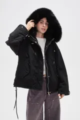 Campera negra de algodón con capucha, cierre frontal oculto y bolsillos laterales. Presenta un diseño holgado con detalles de piel sintética en el borde de la capucha.