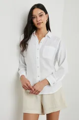 Camisa blanca de algodón con textura arrugada, corte clásico, cuello camisero, manga larga con puños abotonados y bolsillo de parche en el pecho.