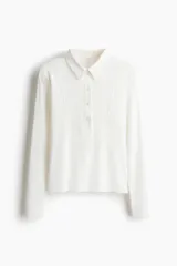 Remera polo de manga larga confeccionada en punto de algodón, con cuello clásico, tapeta frontal con botones y costuras moldeadoras en el frente.