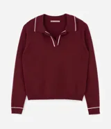 Suéter de punto en color bordó con corte slim, cuello polo y mangas largas. Presenta detalles de líneas blancas en contraste en el cuello y los puños, con acabado acanalado.