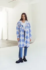 Camisa tipo shacket de corte largo y diseño holgado, con estampado de rombos en tonos celeste, blanco y fucsia. Cuenta con cuello clásico, bolsillos frontales con solapa, cierre de botones y mangas largas con puños abotonados.