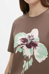 Remera de algodón color beige con estampado frontal de un corazón rosado que contiene un moño. Tiene cuello redondo y mangas cortas.