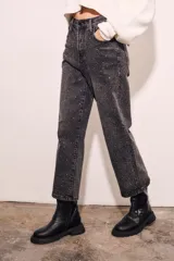Jean de tiro alto, corte recto y largo al tobillo, en color negro lavado con apliques de strass o brillos distribuidos por toda la prenda.