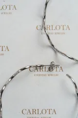Aros tipo argolla con diseño ondulado y orgánico en color plateado.