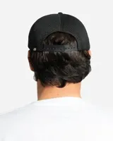 Gorro trucker negro con diseño de malla en la parte trasera y visera curva. Presenta un estampado frontal en color amarillo con tipografía estilo gótico que dice "Mayhem".