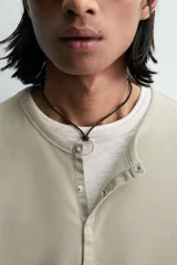 Camiseta de manga larga para hombre con corte relajado, confeccionada en tejido con estructura waffle. Presenta un cuello redondo tipo panadero con cierre frontal de botones a presión.