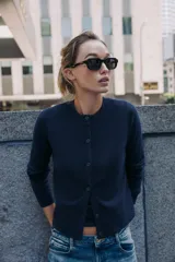 Chaqueta de punto color azul marino, con cuello redondo, manga larga y cierre frontal con botones. Los acabados son en rib a tono.