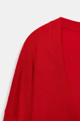 Jersey de punto liso color rojo, con escote en V profundo y mangas largas. Presenta terminaciones en rib en el cuello, puños y ruedo.