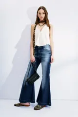 Jean de tiro medio con corte acampanado, ajustado desde la cintura hasta la rodilla y con una apertura pronunciada hacia el ruedo. Presenta un lavado azul localizado con efecto de bigotes y cierre con botón.