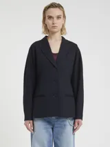 Blazer azul marino de tejido de punto milanés, con solapas de muesca, cierre frontal de dos botones y bolsillos de ojal. Presenta un patrón de rayas finas verticales (pinstripe).