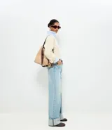 Pantalón de jean corte wide leg con cintura alta, cierre frontal con botón y cremallera, trabillas para cinturón, bolsillos funcionales y bajo con dobladillo ancho plegado.