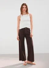 Pantalón de jean marrón de corte wide leg, tiro medio, con bolsillos delanteros aplicados y costuras frontales marcadas.