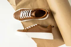 Zapatillas urbanas de cuero, color marrón oscuro, con paneles de gamuza y cuero liso, cordones al tono y suela de plataforma blanca.