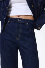 Jean de tiro alto confeccionado en denim de algodón lavado, con diseño de cinco bolsillos y piernas rectas de corte holgado. Cierre frontal con botón y cremallera.